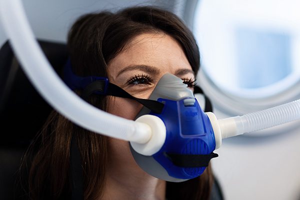 Woman breathing through oxygen mask in hyperbaric chamber.